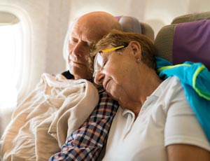 Äldre par sover på flyg