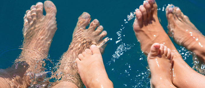 Fötter på vuxna och barn i vattnet