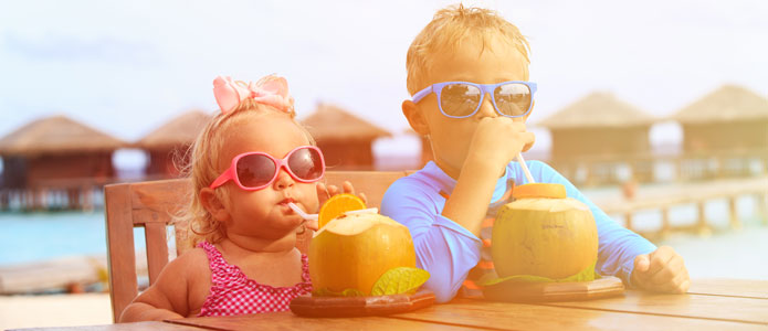 Pojke och flicka dricker saft från kokosnötter