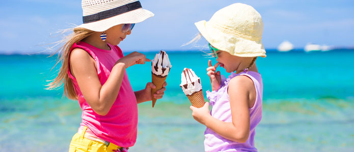 Två små flickor äter glass på stranden